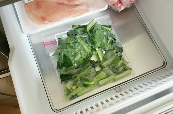 保存袋に入れた生の小松菜を冷凍庫に入れている様子